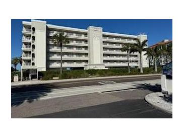 Multi-story building with ocean view, palm trees, and ample parking at 19418 Gulf Blvd # 506, Indian Shores, FL 33785