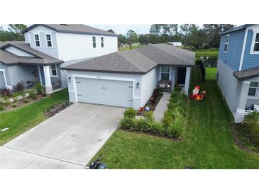 Single-story home with gray garage door, landscaped yard, and walkway at 3329 Fresno Pl, Zephyrhills, FL 33541