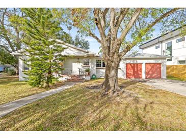 Charming single story home with a large tree and red garage doors at 1023 W Ohio Ave, Tampa, FL 33603