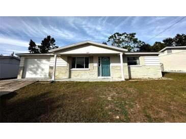 Ranch-style home with a teal door and attached garage at 5027 Farley Dr, Holiday, FL 34690