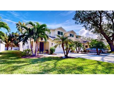 Beautiful two-story home with a well-manicured lawn and lush palm trees at 1957 Whitney Oaks Blvd, Clearwater, FL 33760