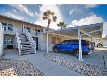 Condo exterior featuring covered parking, stairs, palm trees, and well-maintained landscaping at 201 Silver Lake Dr # 204, Venice, FL 34292