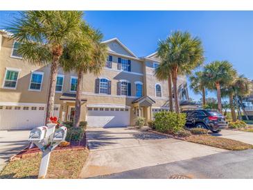 Tan three-story townhome with palm trees, attached garage, and a black SUV parked in the driveway at 3162 Oyster Bayou Way, Clearwater, FL 33759