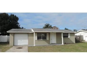 Tan single-story house with attached garage and well-maintained lawn at 9315 Gray Fox Ln, Port Richey, FL 34668