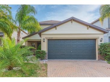 Two-story house with a dark gray garage door and landscaped yard at 10147 Newminster Loop, Ruskin, FL 33573