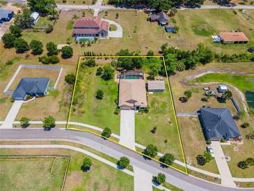 Sprawling property with a sparkling pool, bordered by lush trees and a sunny, well-maintained lawn at 3406 Ranchdale Dr, Plant City, FL 33566
