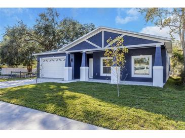 Charming craftsman style home with a navy blue exterior, white accents, and a well-manicured lawn at 302 Archimedes St, Dunedin, FL 34698