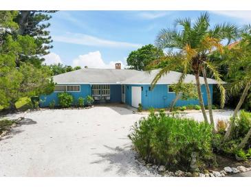 Charming mid-century home with a light blue exterior, white trim, and a gravel driveway at 616 Lyons Ln, Longboat Key, FL 34228