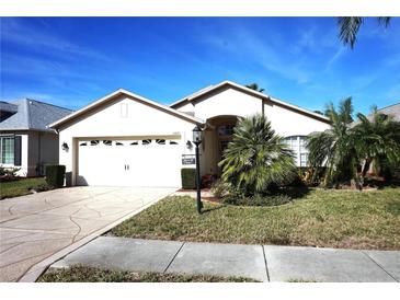 Charming single-story home featuring a two-car garage, manicured lawn, and lush tropical landscaping at 11021 Edge Park Dr, Hudson, FL 34667