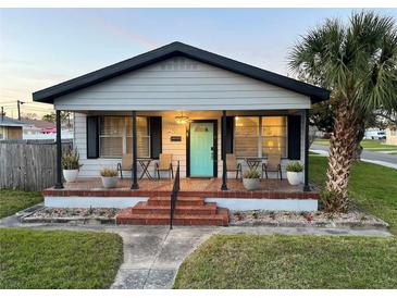 Charming bungalow with a welcoming porch, vibrant blue door, and well-manicured landscaping at 2701 W Cordelia St, Tampa, FL 33607