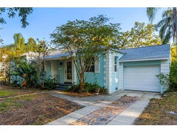Charming blue single-story home features a garage and a brick-lined driveway, enhancing its curb appeal at 2932 W Alline Ave, Tampa, FL 33611