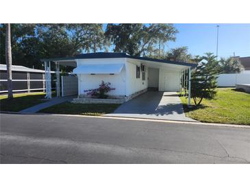 Charming home exterior with a carport, manicured lawn, and mature trees in the community at 27466 Us Highway 19 N # 97, Clearwater, FL 33761