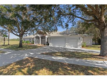 Charming single-story home featuring a spacious three-car garage and covered front porch in a serene, park-like setting at 456 Diamond Dr, Spring Hill, FL 34609