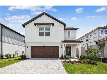 Charming two-story home featuring a brick driveway, attached garage, and manicured landscaping at 6690 Michael Favor Way, Wesley Chapel, FL 33545