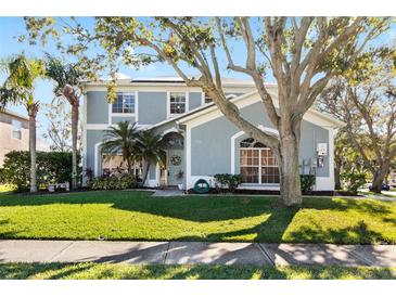 Inviting two-story home featuring a well-manicured lawn, lush tropical landscaping, and a charming entryway at 1600 Gray Bark Dr, Oldsmar, FL 34677