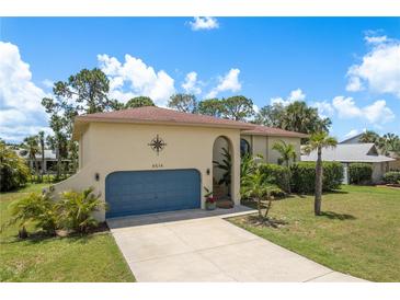Charming single-story home boasts a blue garage door, compass detail, and well-maintained lawn at 4514 Dewey Dr, New Port Richey, FL 34652