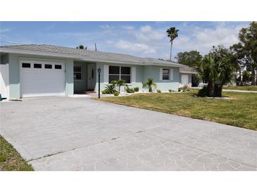 Beautiful one-story home featuring a large driveway, attached garage, well-manicured lawn and updated windows at 123 9Th St, Belleair Beach, FL 33786
