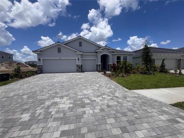 Charming single-story home with a two-car garage, stone accents, a well-manicured lawn, and a paver driveway at 4318 Pullet Ct, Lakewood Ranch, FL 34211