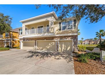 Three-story townhome showcasing a stone base, three-car garage, and balcony on a sunny day at 7001 Interbay Blvd # 313, Tampa, FL 33616