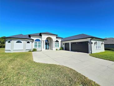 Stunning home featuring a manicured lawn, a wide driveway, and an attached three-car garage at 11199 Warm Wind Way, Weeki Wachee, FL 34613