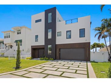 Striking modern home with a two-car garage and a geometrically patterned driveway at 17059 Dolphin Dr, North Redington Beach, FL 33708