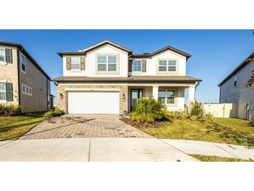 Charming two-story home with a brick driveway, a two-car garage, and manicured landscaping at 7815 Bronze Oak Dr, Wesley Chapel, FL 33545