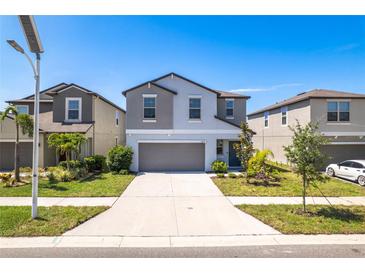 Beautiful two-story home with gray accents, a two-car garage, and landscaped front yard at 16719 Delia St, Wimauma, FL 33598