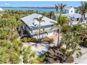 Stunning coastal home with lush landscaping, complemented by a metal roof and scenic water views at 79 Palm Dr, Placida, FL 33946