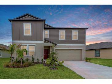 Charming two-story home with a well-manicured lawn and a two-car garage, complemented by a colorful sky at 11307 Linden Depot Rd, San Antonio, FL 33576