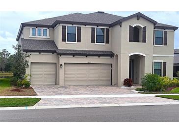 Charming two-story home features a three-car garage and brick-paved driveway at 12854 Boggy Creek Dr, Riverview, FL 33579
