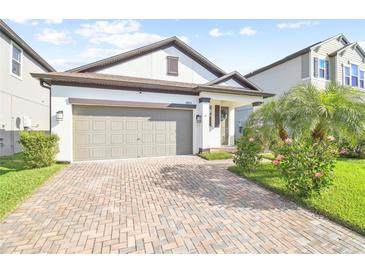 Charming home featuring a brick driveway, two-car garage, and tropical landscaping at 18015 Fenders Way, Land O Lakes, FL 34638