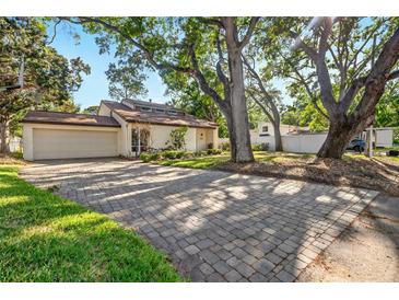 Inviting single-Gathering home featuring a two-car garage and a brick driveway, framed by mature trees at 4822 W San Miguel St, Tampa, FL 33629