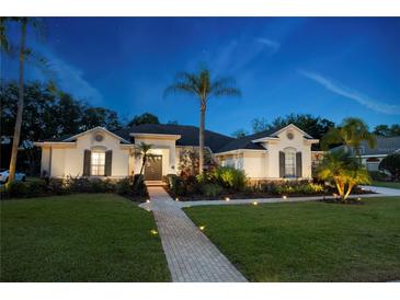 Charming single-story home featuring a well-manicured lawn, landscaped garden, and a brick pathway to the front door at 6020 Kestrel Point Ave, Lithia, FL 33547