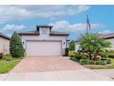 Charming home featuring a brick driveway, manicured lawn, and a two-car garage at 19367 Coastal Shore Ter, Land O Lakes, FL 34638
