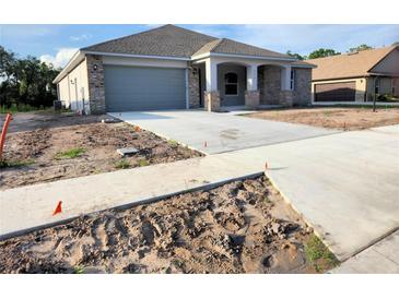 Charming single-story home featuring a gray garage door and a covered porch with brick and stone accents at 422 Shannon Estates Ct, Plant City, FL 33563