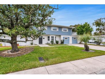 Charming two-story home with a well-maintained lawn, beautiful landscaping, and light blue painted accents at 4902 Stolls Ave, Tampa, FL 33615