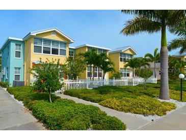 Inviting two-story building with colorful exterior, white picket fence, and lush landscaping at 19417 Gulf Blvd # C210, Indian Shores, FL 33785