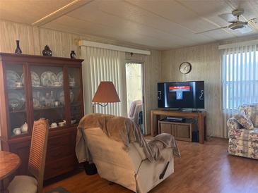 Inviting living room with wood floors, ceiling fan, and a large display cabinet at 12501 Ulmerton Rd # 140, Largo, FL 33774