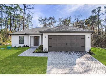 Charming home featuring a gray roof, a two-car garage, and a well-manicured lawn at 1150 Huntington St, North Port, FL 34288