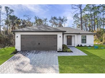 Charming single-story home featuring a paved driveway, two-car garage, and well-manicured lawn at 4621 Kenoska St, North Port, FL 34288
