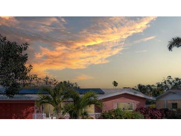 Charming home with lush landscaping and solar panels under a colorful sunset sky at 5166 39Th S St, St Petersburg, FL 33711
