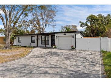 Charming single-story home with well-manicured lawn, gray paved driveway, and attached garage at 4420 Pompano Se Dr, St Petersburg, FL 33705