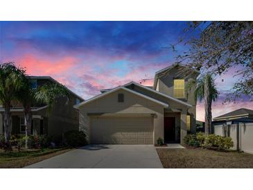 Charming home with a two-car garage, complimented by lush palm trees and twilight skies at 6834 Blue Moon Way, Sun City Center, FL 33573