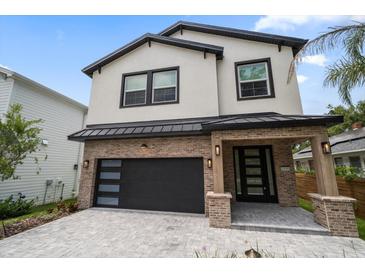 Beautiful two-story home features a brick and stucco exterior with a black garage door and complementary door at 1046 Bass Blvd, Dunedin, FL 34698