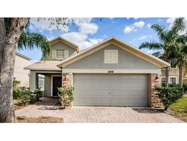 Charming home featuring an attached garage and tropical landscaping with beautiful brickwork and a welcoming front door at 1348 Impatiens Ct, Trinity, FL 34655