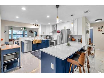 Open kitchen featuring an island with seating, stainless steel appliances, and marble countertops at 1753 Lucas Dr, Clearwater, FL 33759