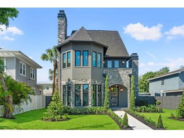 Charming two-story home showcasing stone accents, a well-manicured lawn, and lush landscaping at 807 W Park Ave, Tampa, FL 33602