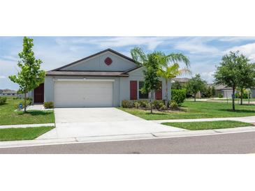 Charming single-story home with a two-car garage, well-maintained lawn, and lush landscaping at 9805 Lemon Drop Loop, Sun City Center, FL 33573