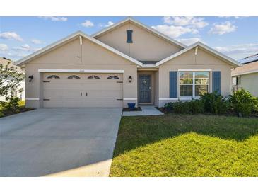 Charming single-story home featuring a two-car garage and well-maintained lawn with blue shutters and a welcoming entrance at 12143 Kingsley Trl, Parrish, FL 34219