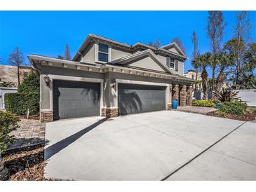 Beautiful exterior with a three car garage, paver driveway, stone accents and lush landscaping at 5701 S Macdill Ave, Tampa, FL 33611